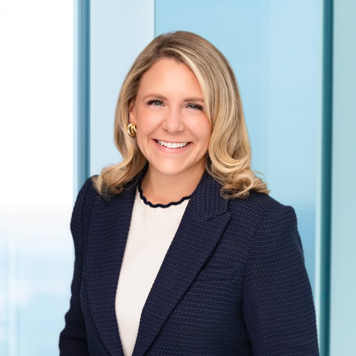 Becky Hudson headshot, blonde woman on blue corporate background