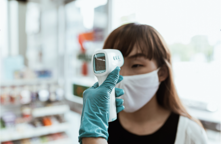 Woman wearing a face mask, getting her temperature taken